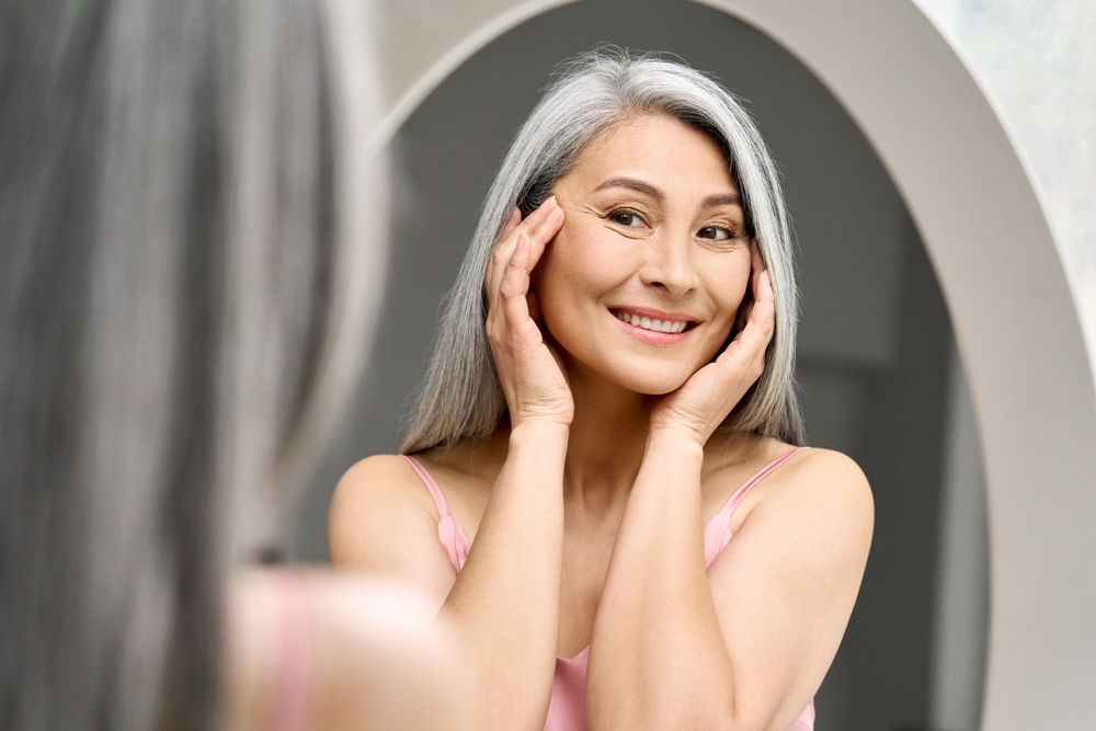 Woman smiling in mirror, showcasing natural beauty.